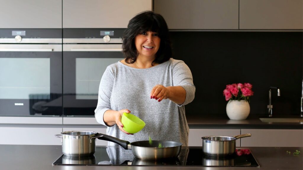 Woman in kitchen cooking facing the camera